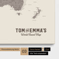 Personalisierung einer Weltkarte Pinnwand in Warmgray (Braun-Grau) mit einem Logo im Vintage-Look, bei dem die Namen und die Unterzeile „World Travel Map“ geändert werden kann